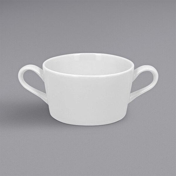 A RAK Porcelain white porcelain soup bowl with two handles on a gray surface.