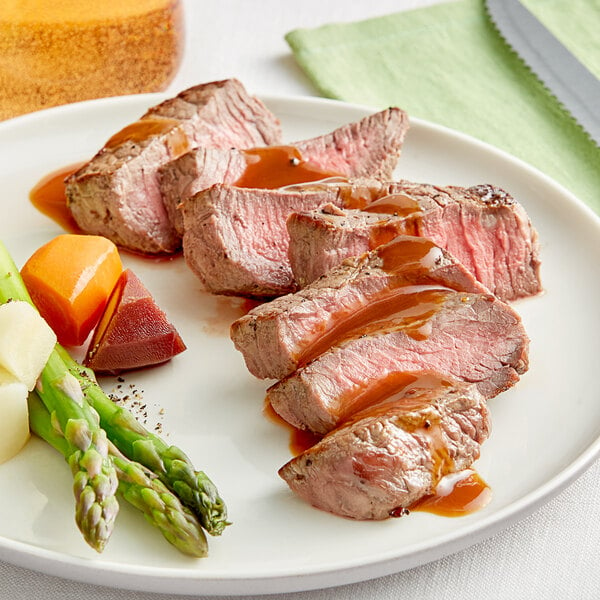 A plate with a Rastelli's Black Angus Coulotte Steak, asparagus, and sauce.
