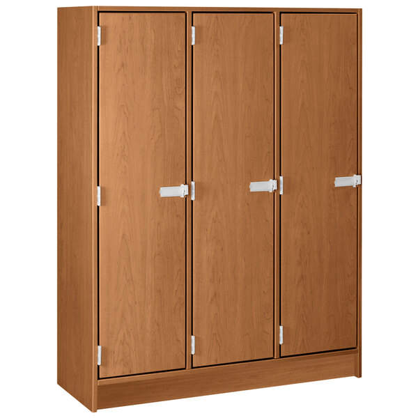 A medium cherry wooden locker with three doors with white handles.