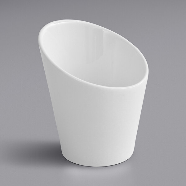 A white Fortessa porcelain cup with a slanted bottom and small handle on a gray surface.