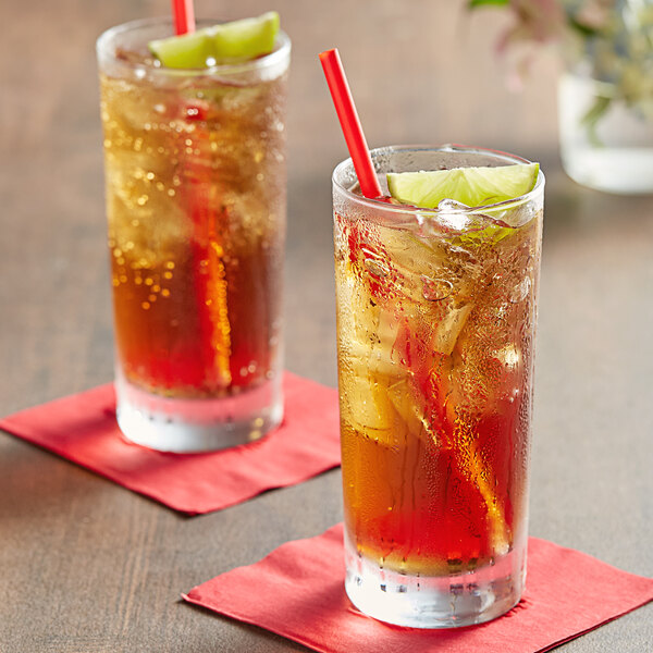 Two glasses of Tractor Beverage Co. Organic Cola with straws and lime slices.