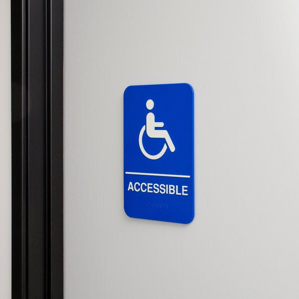 A blue and white Thunder Group ADA Handicap Accessible sign on a wall.