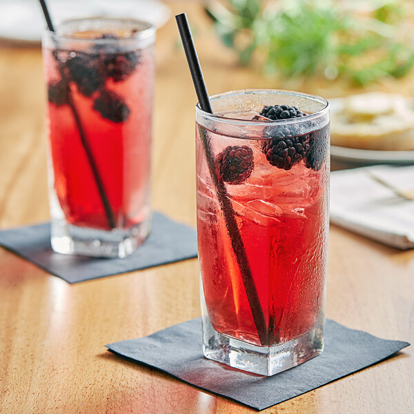 Two glasses of Tractor Beverage Co. Organic Blackberry juice with black straws on a table.