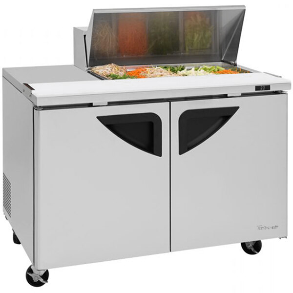 A Turbo Air stainless steel refrigerated sandwich prep table with glass doors on top.
