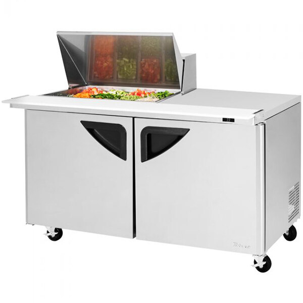 A white Turbo Air Super Deluxe refrigerated sandwich prep table with food on the counter.
