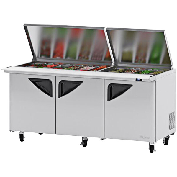 A Turbo Air Super Deluxe refrigerated sandwich prep table with flat lid open on a food buffet.