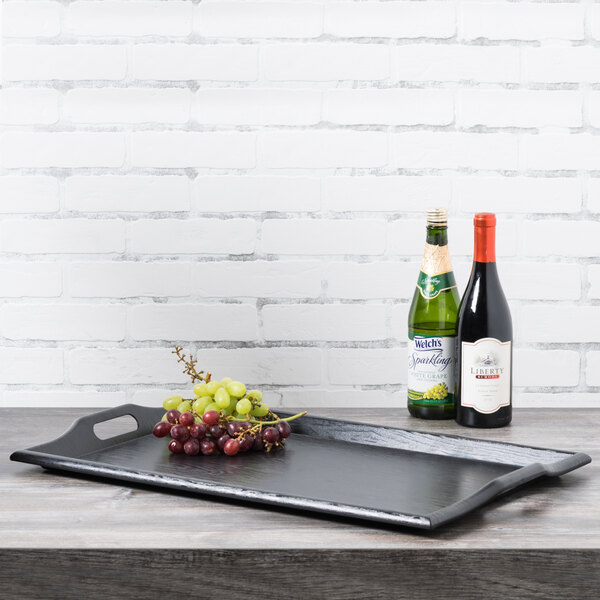 A black GET plastic room service tray with grapes and bottles of wine on it.
