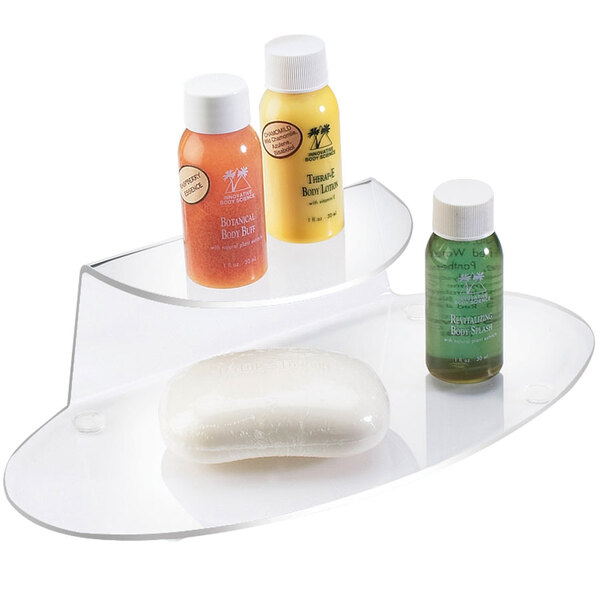 A clear Cal-Mil amenity shelf with a bar of soap and bottles of body lotion.
