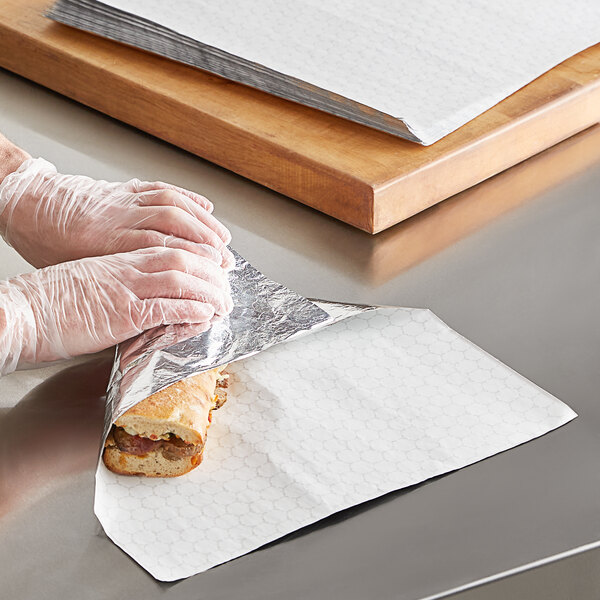 A person in plastic gloves wrapping a sandwich in Choice insulated foil.