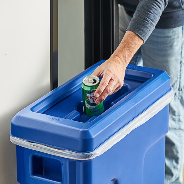 A man putting a blue Toter recycling lid on a trash can.