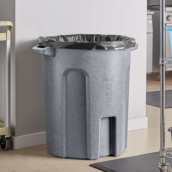 A Toter dark gray granite round trash can on a floor with a black liner.