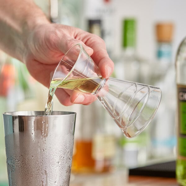 A hand using a Franmara plastic double jigger to pour liquid into a glass.