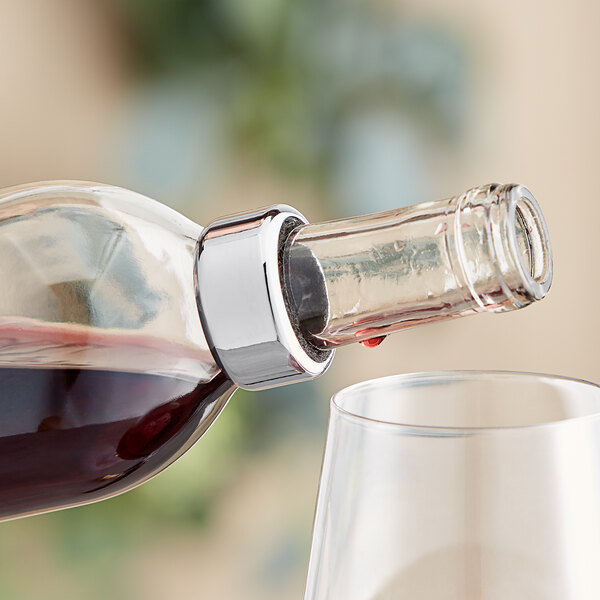 A Franmara stainless steel wine collar around a wine bottle on a table with a glass of wine.