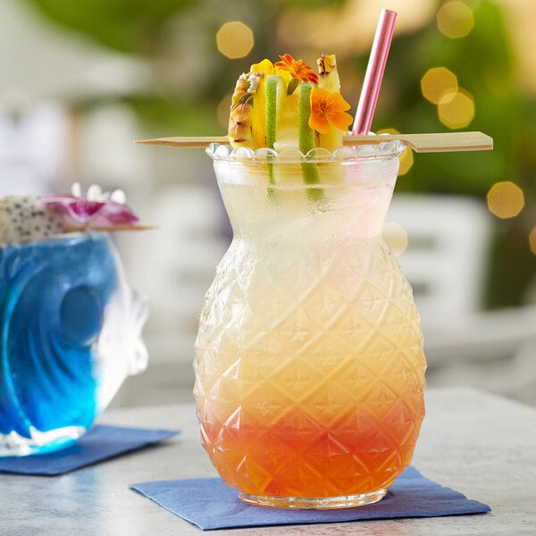 A close up of an Acopa Pineapple Glass with a drink containing pineapple and fruit.