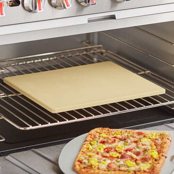 A rectangular pizza stone with a pizza cooking on it in an oven.