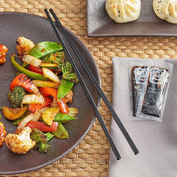 A plate of vegetables and broccoli with GET black melamine chopsticks on a table.