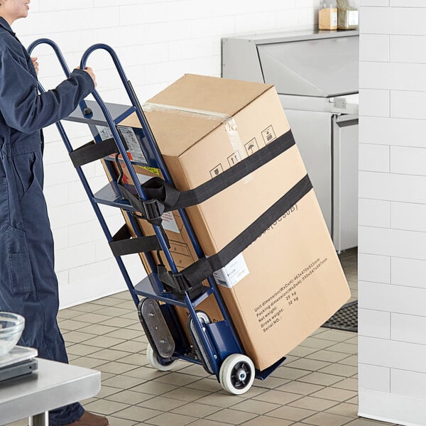 A man in a blue uniform using a Lavex blue appliance hand truck to move a box.