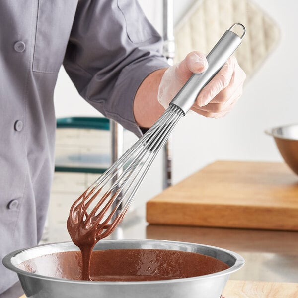 A person mixing chocolate batter with a Choice stainless steel French whisk.