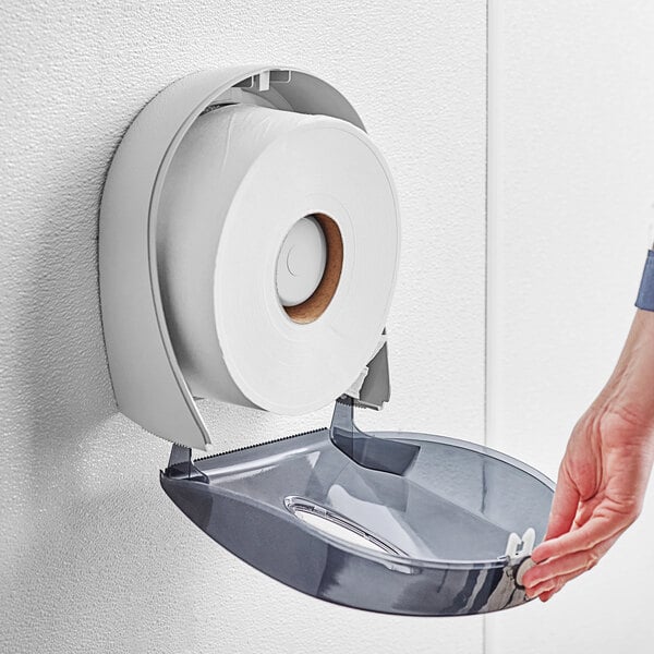 A hand reaching out to a roll of Pacific Blue toilet paper on a dispenser.