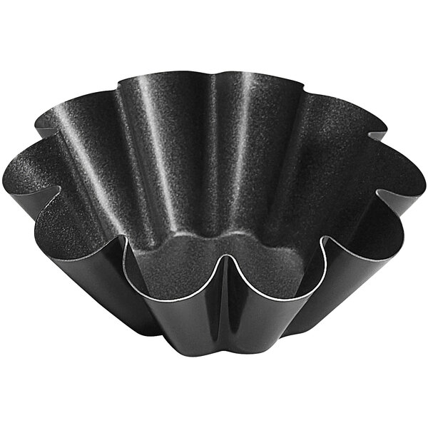 A black metal Gobel fluted brioche mold with wavy edges.