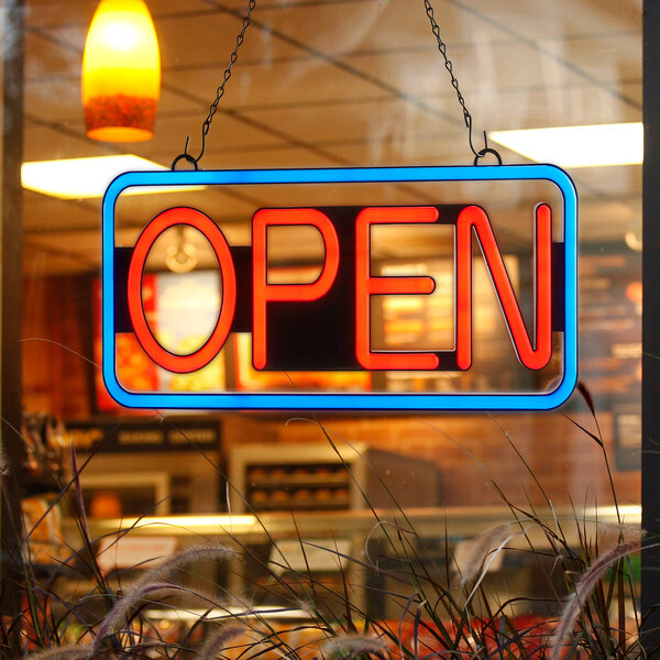 A rectangular blue and red LED neon sign that says "Open" on a window.