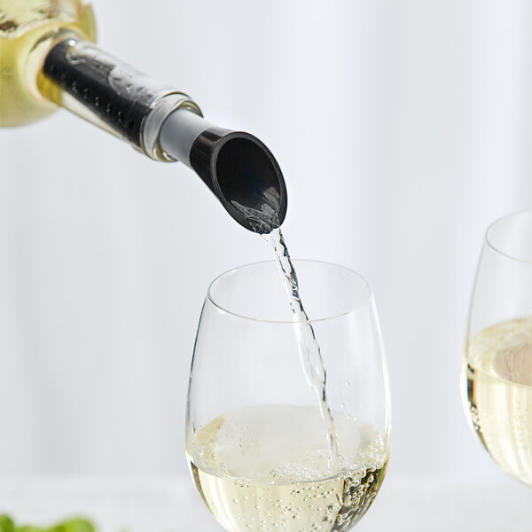 A person using a Franmara black perforated wine pourer to pour white wine into a glass.