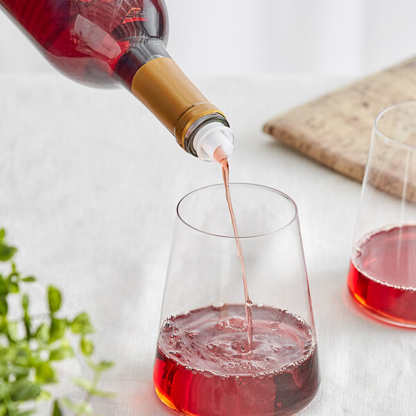 A Franmara green plastic screwtop wine pourer on a bottle pouring red wine into a glass.