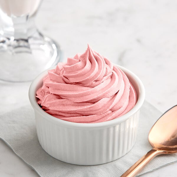 A bowl of pink Creamery Ave. Strawberry soft serve with a spoon.
