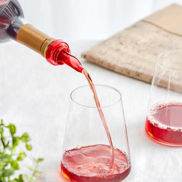 A person using a Franmara red wine pourer to pour red wine into a glass on a table.