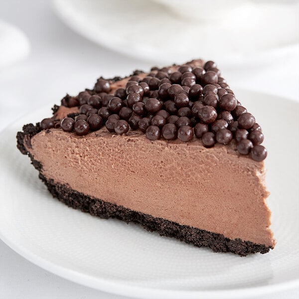 A slice of chocolate pie with Mona Lisa dark chocolate crispearls on top.