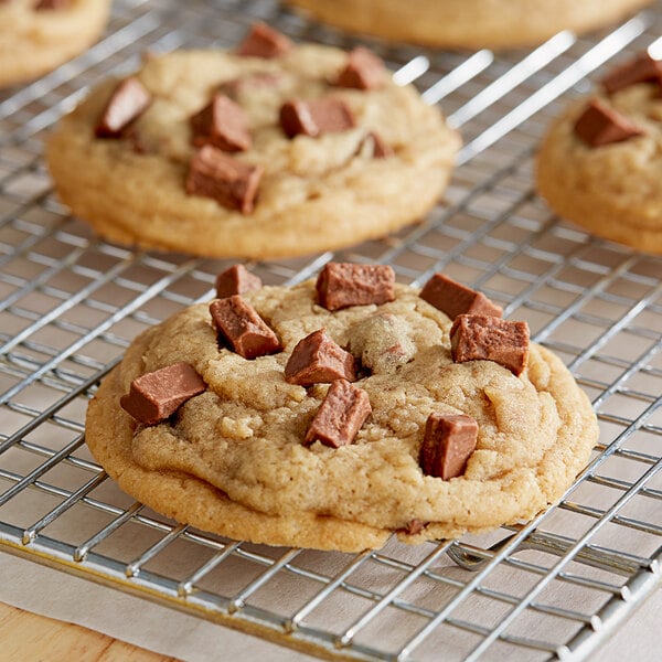 A chocolate chip cookie on a cooling rack with Van Leer milk chocolate chunks on top.