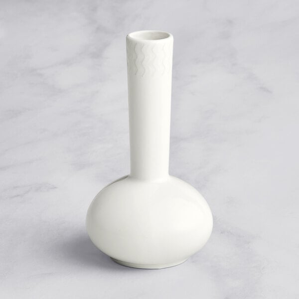 A close up of a RAK Porcelain Leon ivory vase with an embossed design on a marble surface.