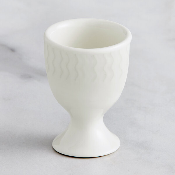 A RAK Porcelain ivory egg cup with an embossed design and a small handle.
