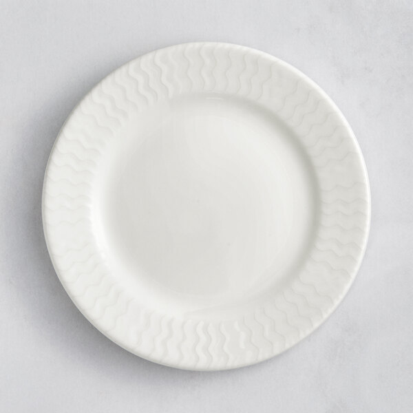 A white RAK Porcelain Leon flat plate with wavy lines on the rim.