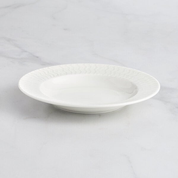 A RAK Porcelain ivory deep plate with an embossed pattern on a marble surface.