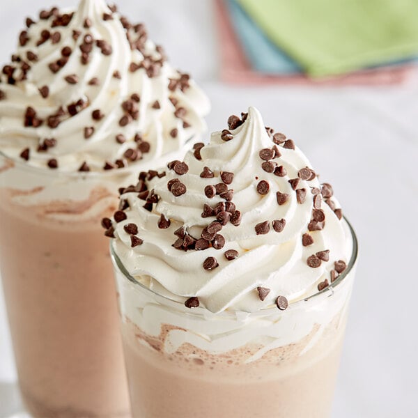 Two glasses of chocolate milkshakes with whipped cream and Barry Callebaut semi-sweet chocolate chips on top.