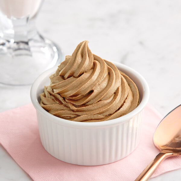 A bowl of brown soft serve ice cream with a spoon.