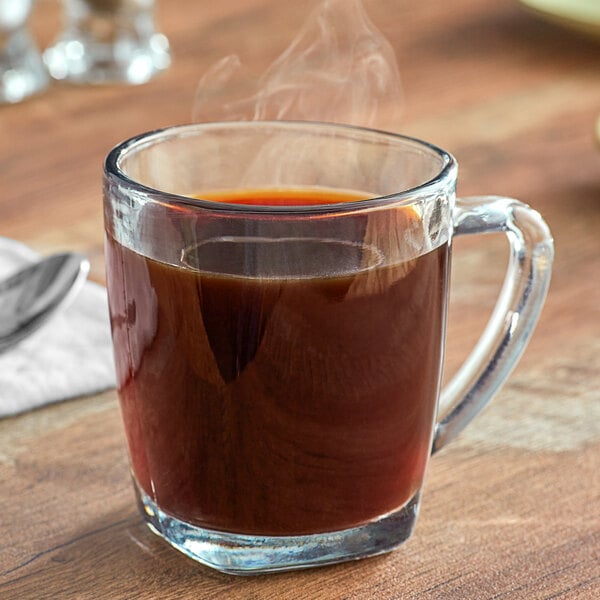 A glass cup of Crown Beverages Royal Reserve Sumatra Decaf Whole Bean Coffee with steam coming out of it.