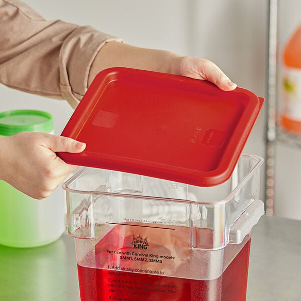 A person holding a red lid over a clear container.