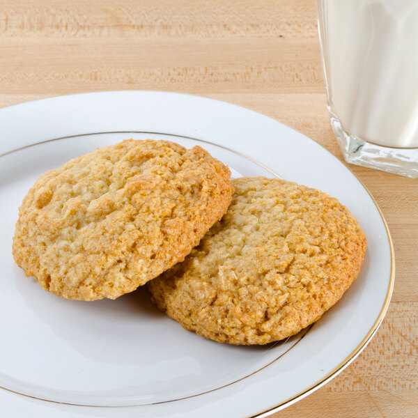 A plate with two sugar cookies next to a glass of milk.