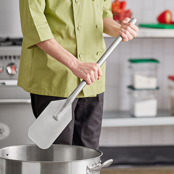 A person using a Fourt&#233; stainless steel paddle in a pot.