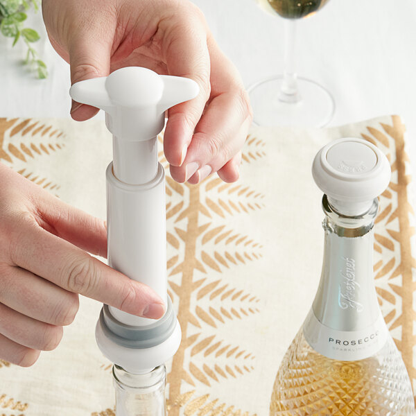 A hand using a white Franmara VinoVac pump to seal a bottle of wine.