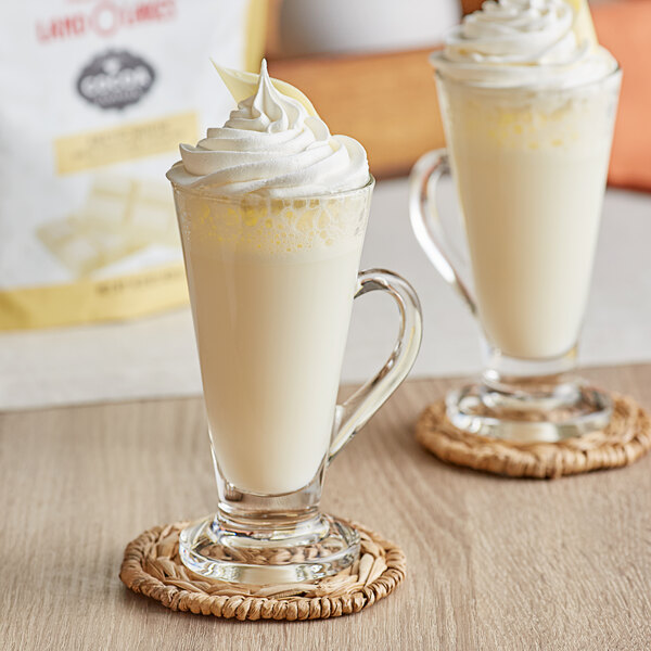 Two glasses of Land O Lakes Arctic White Chocolate Cocoa with whipped cream on top.