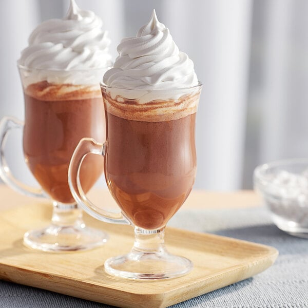 Two glass mugs of Land O Lakes chocolate cocoa with whipped cream.