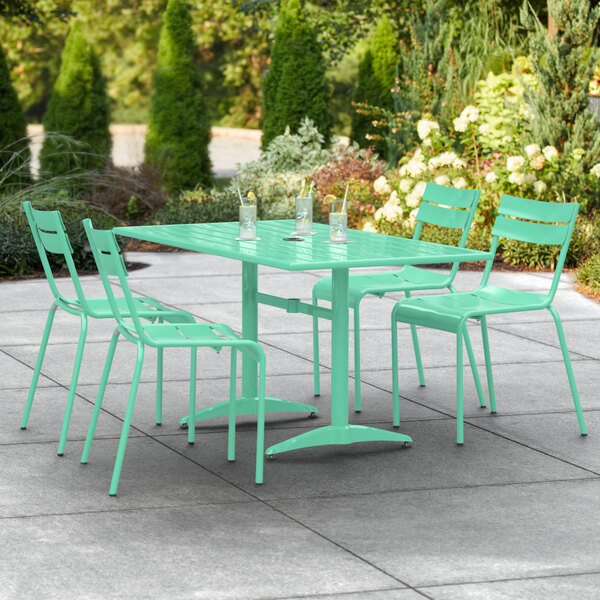 A Lancaster Table & Seating sea foam green powder-coated aluminum table with chairs on a patio.