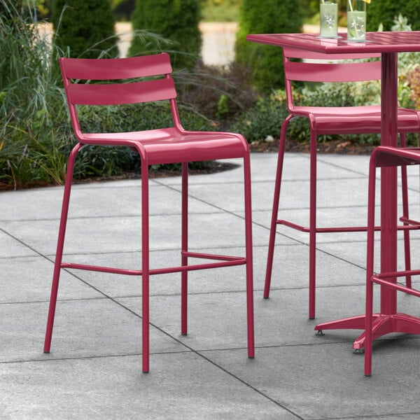 A red Lancaster Table & Seating outdoor barstool on a patio table.