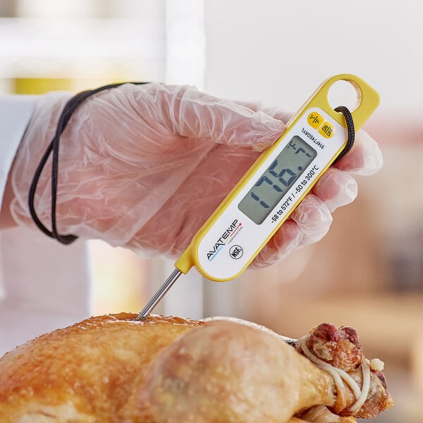 A person holding the yellow AvaTemp digital folding probe thermometer over a turkey.
