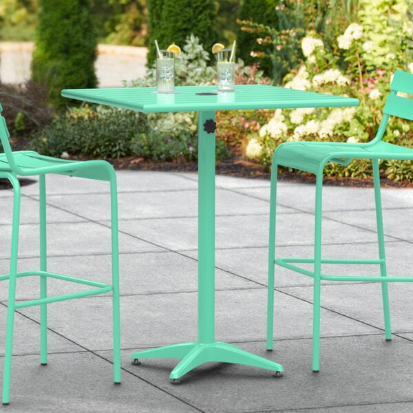 A Lancaster Table & Seating sea foam green aluminum bar table on a patio.