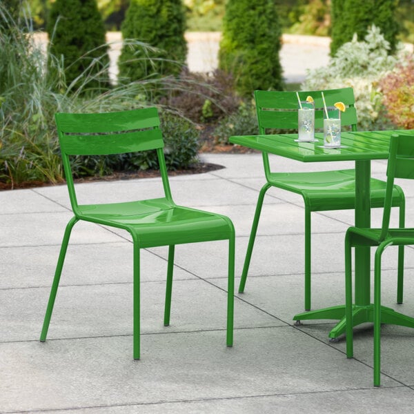 A green table and chairs on a patio with drinks.