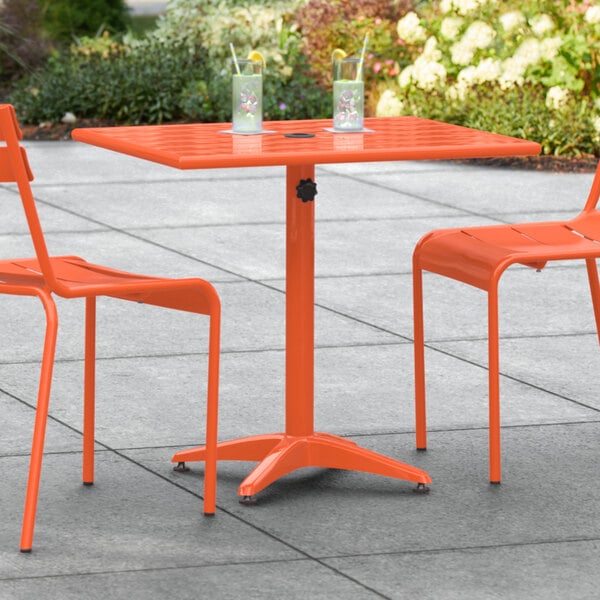 A Lancaster Table & Seating orange table with chairs on a patio.